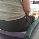 Restorative Seated forward Fold in Staff Pose, with wedge, blankets and cushions for support.