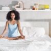 Young African American Woman Doing Yoga In Bed After Sleep